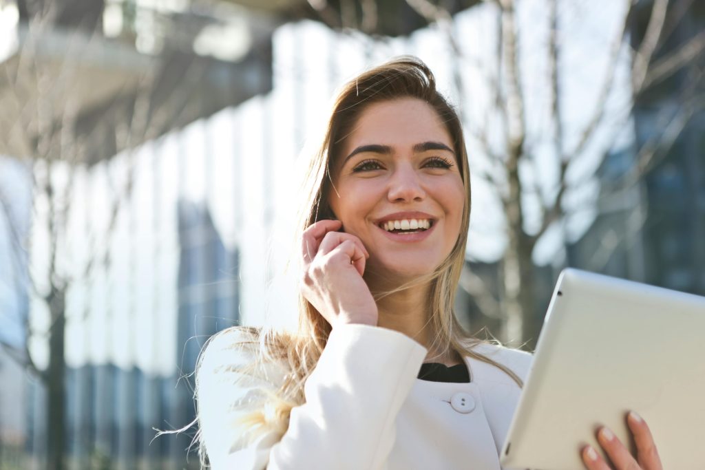 pexels-photo-789822-789822 Confident businesswoman using her tablet and phone, smiling outdoors in sunlight.